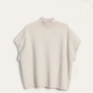 Beige stickad ärmlös topp - Säljer en stilren beige stickad topp med hög krage. Den är ärmlös och har en ribbad kant vid halsen och nederkanten. Perfekt för lager-på-lager eller som den är.