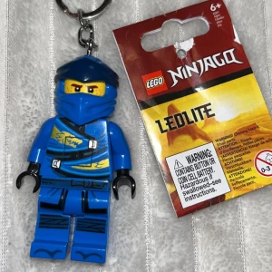 LEGO Ninjago LED-nyckelring (Jay) - LEGO Ninjago Jay nyckelring med LED-lampa. 8 cm hög. rutan på Magen är knappen för ficklampan. Benen går att röra sig som en vanlig lego figur och händerna går att ta av. Köpt för 200kr. 