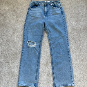 Blå jeans med slitning 40 NA-KD - Snygga blå jeans med en cool slitning på vänster ben. De har en klassisk femficksdesign och en rak passform som ger en avslappnad look. Perfekta för en casual stil.