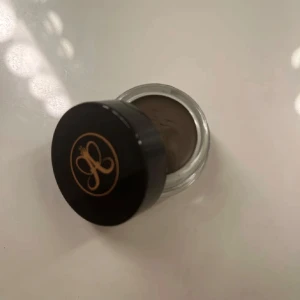 Dipbrow Pomade i SoftBrown - Säljer en nästan ny Dipbrow Pomade frän Anastasia Beverly Hills i färgen Soft Brown. Perfekt för att forma och fylla i ögonbrynen med en naturlig look. 💕 Kommer i en snygg glasburk med svart lock och guldlogga. Perfekt för bäde vardag och fest! (Endast testad! Färgen var tyvärr fel för mina ögonbryn) orginal pris: 250kr💸