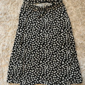 Svart blommig kjol från Soul River - Snygg svart kjol med vita blommor från Soul River. Perfekt för en stilren look med sitt blommiga mönster. Kjolen har en bekväm passform och är lätt att matcha med olika toppar.