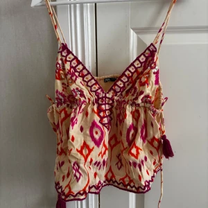 Broderad topp från Zara - Superfin populär sommar topp från Zara, stan inte att toppen är använd som ny! Toppen har smala axelband, snörning framtill och tofsar i sidorna. 