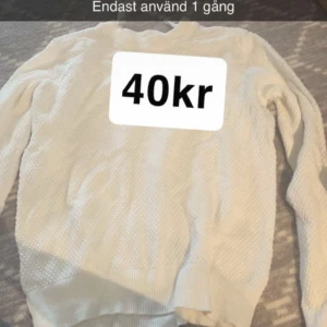 Vit stickad tröja med struktur - Säljer en vit stickad tröja med snygg struktur och rund hals. Tröjan har långa ärmar och ribbade muddar vid ärmslut och nederkant. Perfekt för dig som gillar en enkel men stilren look.