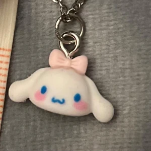 Sanrio Cinnamoroll Halsband Choker cute - Sött halsband med en liten berlock av Cinmamoroll. Berlocken är ca 1,6 x 0,8 cm. Trädd på kedja i silver imitation som är justerbar 35-40 cm, så du kan välja om det ska sitta som en choker eller lite längre ned. 