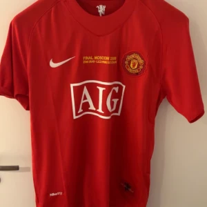 Manchester United Ronaldo 7 Finaltröja - Manchester Uniteds officiella matchtröja från Champions League-finalen 2008 i Moskva. Röd med vita och gula detaljer, AIG-logga, klubbmärke, Nike FITDRY-material och Champions League-märke på ärmen. Ryggen har Ronaldo och nummer 7 i silver.