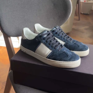 Valentino flycrew sneakers blå - Snygga flycrew sneakers från Valentino i blå mocka och vitt skinn. Skorna har svarta skosnören, vit sula med nitar baktill och rund tå. Perfekta för dig som gillar stilrena och exklusiva sneakers. Og all och skick 7/10 (2 nitar av, lite trött mocha). Perfekt hela året om!