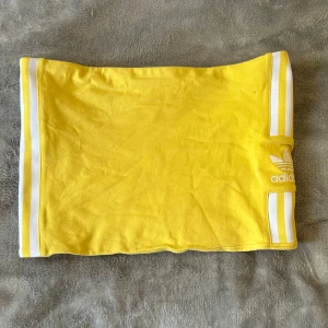 Gul Adidas mini kjol med vita ränder - Gul minikjol, Lågmidjad och kort från adidas i storlek 38 men skulle säga passar XS/S. Superfint och fint skick, inga defekter. Perfekt till sommaren! Säljer då den inte kommer till användning💛