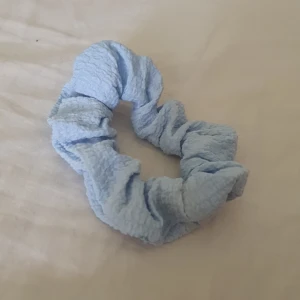 Ljusblå scrunchie - En söt ljusblå scrunchie i mjuk bomull med rynkad textur. Perfekt för att sätta upp håret med en chill och trendig look. Enkel att matcha med olika outfits och skonsam mot håret.