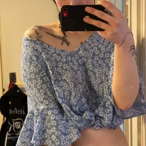 Blommig blå blus med volangärm •V-ringad - Supersöt ljusblå blus med vita blommor och v-ringning. Trekvartsärmar med volangkant ger en chill vibe. Toppen är lätt croppad, jag själv brukar knyta den framtill (se bilder). Perfekt för vår och sommar, i mjuk bomull som känns skön mot huden. Lappen borta, vet ej exakt storlek men passar alla storlekar mellan XS upp till L