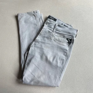 Replay Anbass - Snygga ljusgrå Replay Anbass jeans med klassisk femficksdesign och diskret logga på fickan.                                                                Jeansen är i toppenskick!