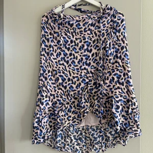 Leopardmönstrad volangkjol i blått och rosa, storlek S - Säljer en flowy kjol med blått och rosa leopardmönster. Kjolen har volangkant nertill och knytband i midjan. Från Levete, storlek S. Inga anmärkningar