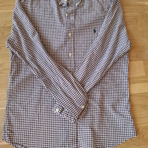 Rutig skjorta från Polo Ralph Lauren - Snygg rutig skjorta från Polo Ralph Lauren i vitt och mörkblått. Skjortan har klassisk krage, knäppning framtill och lång ärm. Slim fit-modell med broderad logga på bröstet.