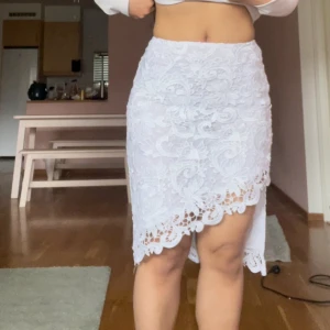 Vit spetskjol från Guess - Supersnygg vit kjol från Guess med spets och broderade detaljer. Kjolen har asymmetrisk nederkant och sitter tajt över höfterna. Perfekt för dig som vill sticka ut med en feminin och elegant look. Fodrad insida för extra komfort.