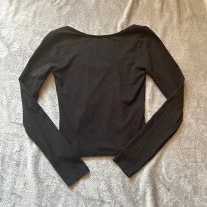 Svart långärmad topp Gina Tricot - En svart långärmad topp från Gina Young med lite öppen rygg, superbra skick, endast använd 1 gång. Storlek 158/164 men passar även XS❤️