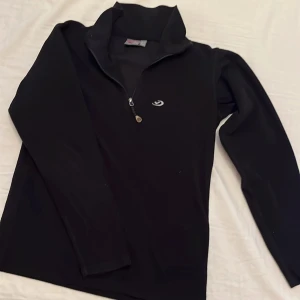 Svart fleecetröja från Five Seasons, underställ  - Säljer en svart fleecetröja/ underställströja från Five Seasons i storlek 146/152.. Tröjan har en dragkedja vid halsen och är perfekt för kyliga dagar. Den är i mycket bra skick och passar bra för både vardag och utomhusaktiviteter.