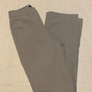 Gråa kostymbyxor från Bik Bok - Snygga gråa kostymbyxor från Bik Bok i storlek 36. Byxorna har raka ben, hällor för bälte och diskreta sidfickor. Perfekta för en clean och stilren look. Materialet känns mjukt och har en lätt stretch för extra komfort.