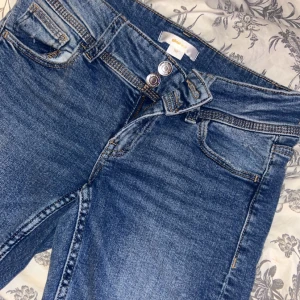 Blå jeansbyxor från Ginatricot - Snygga blå jeansbyxor från Ginatricot med klassisk femficksdesign, dubbla knappar i midjan och bakfickor med lock och knapp. Jeansen har en normal passform och är tillverkade i mjukt denimtyg som sitter skönt hela dagen.