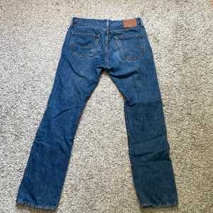 Levi's 501  blå jeans 32/32 - Klassiska Levi's 501 Premium jeans i blå denim. Rak passform med fem fickor, knappgylf och snygga kontrastsömmar. Tidlös modell med normal midja och ikonisk läderpatch bak. Perfekta för dig som gillar en clean och autentisk jeanslook.