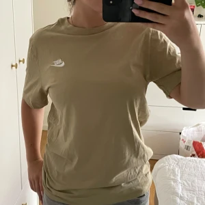 Beige t-shirt från Nike - Säljer en beige t-shirt från Nike med klassisk logga på bröstet. T-shirten har rund halsringning och korta ärmar. Knappt använd.