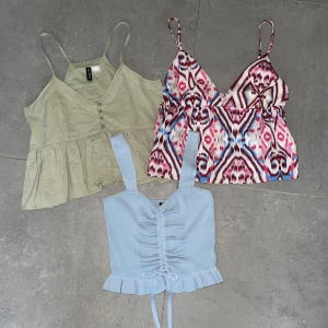 3 somriga toppar i olika stilar - Tre snygga toppar: en ljusgrön blus från H&M med broderade blommor, knappar och volangkant, en färgglad mönstrad topp med smala axelband och knyt i sidan från Shein, samt en ljusblå stickad topp från H&M med breda axelband, volangkant och snörning framtill. Den gröna och den mönstrade är endast provade. Den blå är använd ett fåtal gånger.