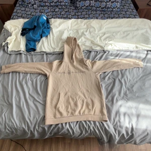 Beige hoodie från Sail Racing 160-164cm i junior  - Säljer en beige hoodie från Sail Racing med tryckt logga på bröstet. Tröjan har huva, magficka och långa ärmar. Perfekt för dig som gillar en clean och enkel stil. Materialet känns mjukt och skönt, troligtvis bomull eller bomullsblandning.