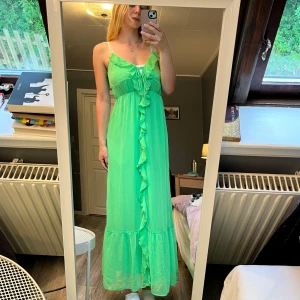 Grön maxiklänning från Gina Tricot Prislapp kvar - Superfin lång grön klänning från Gina Tricot i luftig chiffong. Klänningen har smala axelband, volangdetaljer framtill och knytning vid bysten. Perfekt för sommarens alla tillfällen och ger en riktigt fräsch vibe. Helt ny oxh oanvänd med kvitto