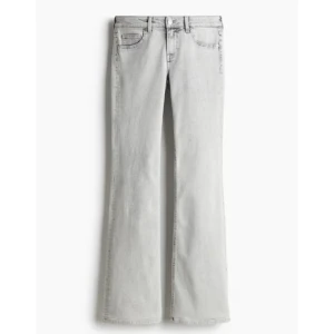 Gråa bootcut jeans från H&M Divided - Snygga gråa bootcut jeans från H&M Divided med klassisk femficksdesign och dragkedja. Jeansen har en ljusgrå tvätt och är tillverkade i bomullsmix med lite stretch. Perfekta för dig som gillar en retroinspirerad look med utsvängda ben.