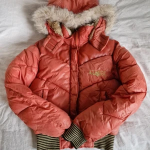 Y2K-jacka med pälsluva - Cool dunjacka i 2000s-stil från Icy Babe 🎀 Orange, fluffig modell med (fake)päls på luvan och mysigt foder! :)                                           Luvan är avtagbar. Sann till storlek (176/S)                                                     Finns några små skavmärken på ryggen, se de sista bilderna. I övrigt är jackan i perfekt skick!                                                         Pris är självklart förhandlingsbart 😊                 Hör gärna av er vid frågor! 💕