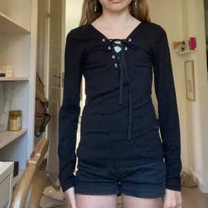 Svart ribbad långärmad tröja med snörning - Svart långärmad tröja från H&M med ribbad struktur och snygg snörning framtill vid halsen. Tröjan har en tight passform och är perfekt för dig som gillar en stilren men ändå trendig look. Materialet är mjukt och stretchigt, vilket gör den superbekväm. Pris går att diskuteras 