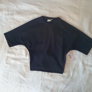 Svart topp med knyt från Nelly - Fin tröja med knyte på ryggen från Nelly! Väldigt fint skick och säljes pågrund av att den inte används🩷