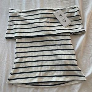 Randig offshoulder topp från NA-KD - Superfin offshoulder topp från NA-KD i vitt med svarta ränder. Materialet är stretchigt och perfekt nu till sommaren. Helt ny med prislappen kvar, aldrig använd bara provad. 