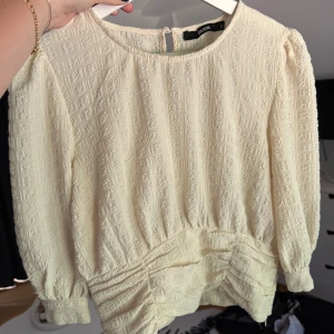 Topp med tight midja - Supersöt vit/krämfärgad topp från BikBok med tight midja och trekvartsärm! Endast använd 1 gång så toppen är i väldigt fint skick 🩷Säljer då den inte passar mig längre.