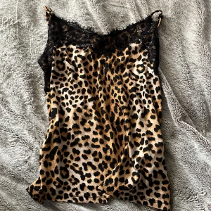Leopardmönstrad linnetopp med spets - Snygg leopardmönstrad linnetopp med svarta spetsdetaljer upptill. Tunt och lätt material med smala axelband. 