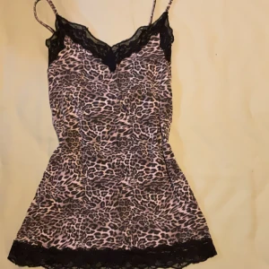 Leopardmönstrad linnetopp från Tezenis - Säljer en snygg leopardmönstrad linnetopp från Tezenis med tunna axelband och svarta spetsdetaljer vid halsringning och nederkant. Toppen har en figurnära passform och är perfekt för dig som vill sticka ut med ett djurmönster. Superfin att styla med jeans eller kjol!