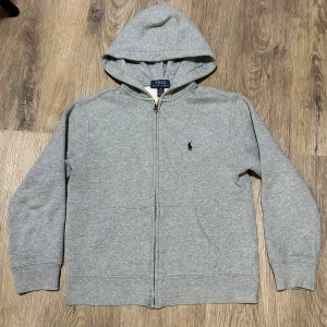 Grå hoodie från Polo Ralph Lauren - Jag säljer den här polo zip hoodien för att den är för liten för mig. Den är i bra skicka på en skala 1/10 skulle jag säga 9/10⭐️ Köptes på kidsbrandstore för 1200kr mitt pris 500kr. Om ni har några frågor är det bara att skriva!