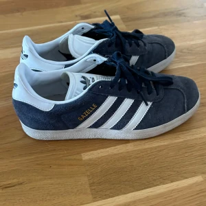 Adidas Gazelle sneakers blå - Säljer dessa snygga Adidas Gazelle sneakers i mörkblå mocka. Dom är i mycket bra skick då jag inte använt dom några få gånger. Hör av er vid funderingar 