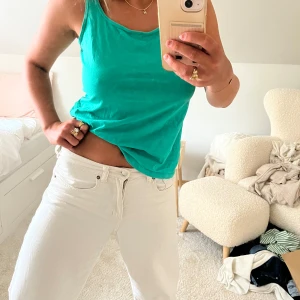 Turkos linnetopp i bomull - Snygg turkos linnetopp med klassisk rund halsringning och ärmlös design. Toppen är i mjuk bomull och har en enkel, stilren look som passar perfekt till jeans eller shorts. Perfekt för varma dagar när du vill ha något lätt och bekvämt.