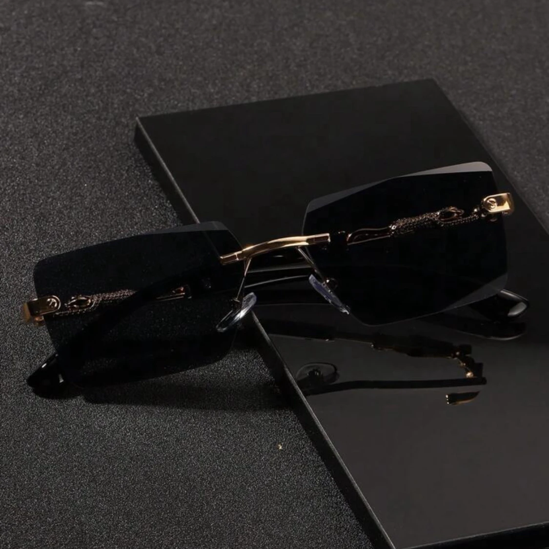 Svarta rektangulära solglasögon med gulddetaljer