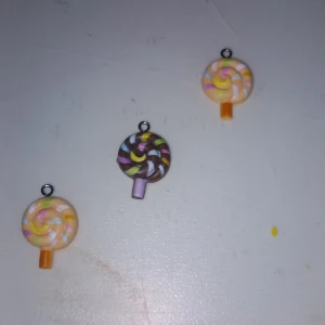 Färgglada klubba-halsbandsberlocker - Tre söta berlocker formade som klubbor i pastellfärger. Två är i ljusa toner av rosa, gult, vitt och blått, och en är i brunt, grönt, rosa och vitt. Perfekta att använda som hänge till halsband eller armband för en lekfull look.