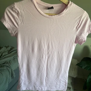 Ljusrosa t-shirt från Gina Tricot - Säljer min ass söta T-shirt från Gina tricot, tröjan är andvänd men i bra skick den är tajt och är perfekt om man vill ha en clean look
