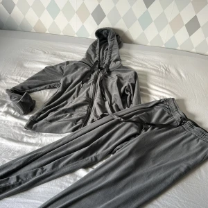 Gråa mjukisbyxor med dragsko - Mysiga grå mjukisbyxor med elastisk midja och dragsko. Byxorna är i mjukt material och har en avslappnad passform, perfekta för chill dagar hemma eller när du vill vara bekväm. Matchar snyggt med en hoodie eller t-shirt.