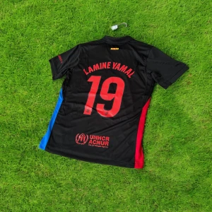FC Barcelona svart bortatröja Nike - Snygg svart FC Barcelona bortatröja från Nike med röda och blå sidopaneler, tryckta loggor från Spotify och UNHCR samt namn och nummer Lamine Yamal 19 på ryggen. Tröjan har korta ärmar och är tillverkad i lätt, ventilerande funktionsmaterial.