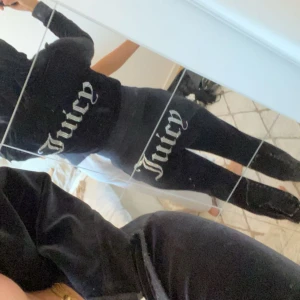 Svart Juicy Couture mjukis sett - Svarta mjukisbyxor och zip hodie från Juicy Couture med glittrande Juicy-text i strass över rumpan. Byxorna har hög midja och är i mjuk, stretchig sammet som sitter tight. Knappt använt, 600kr för hela sättet