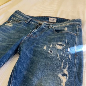 Tiger of Sweden jeans - Ett par ToS jeans med snygga slitningar. Modellen Rex är såld med färdiga slitningar som ska se lagade ut alltså inget som försämrar hållbarheten. Mörkblå coola jeans som passar till de flesta stilarna