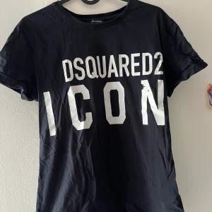Svart Dsquared2 ICON t-shirt - Cool svart t-shirt från Dsquared2 med stor vit 'ICON'-text framtill. Klassisk rund halsringning och korta ärmar. Perfekt statement-plagg för dig som gillar streetstyle och vill sticka ut med en ikonisk look.