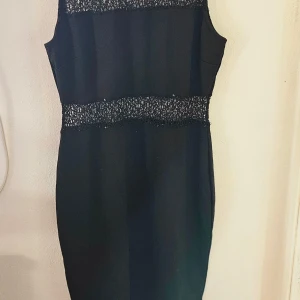 Svart spetsklänning Gina Tricot XL - Svart ärmlös kortklänning från Gina Tricot i storlek XL. Klänningen har snygga spetsdetaljer upptill och i midjan som ger en cool kontrast till det släta tyget. Figurnära passform och perfekt för dig som gillar stilren men ändå unik look. Tvättnoppror finns 