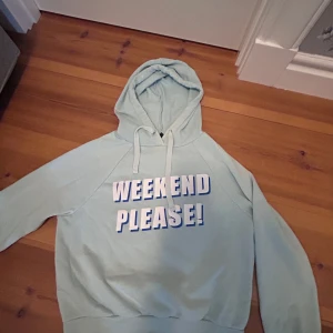 Ljusblå hoodie från Gina Tricot - Ljusblå hoodie från Gina Tricot med trycket 'Weekend please!' i vitt och blått framtill. Tröjan har huva med snörning och långa ärmar. Mjuk o mysig insida och klassisk passform.