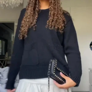 Svart stickad tröja från Zara - Svart stickad tröja från Zara med två stora fickor framtill och ribbade muddar vid ärmslut och nederkant. Tröjan har en avslappnad passform och rund halsringning, perfekt att styla med kjol eller jeans för en chill look.