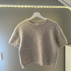 Beige stickad tröja Gina Young - Supermjuk och fluffig beige stickad tröja från Gina Young. Modellen är boxig med korta ärmar och rund halsringning. Använd ett fåtal gånger!💗