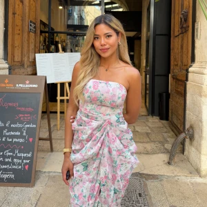 Blommig axelbandslös långklänning - Superfin axelbandslös långklänning från PrettyLittleThing med blommigt mönster i rosa, grönt och vitt. Draperade detaljer framtill ger en romantisk känsla – perfekt för sommarfester, middagar eller en semesterkväll i Italien. Figurnära passform med en feminin siluett som sitter jättefint! 